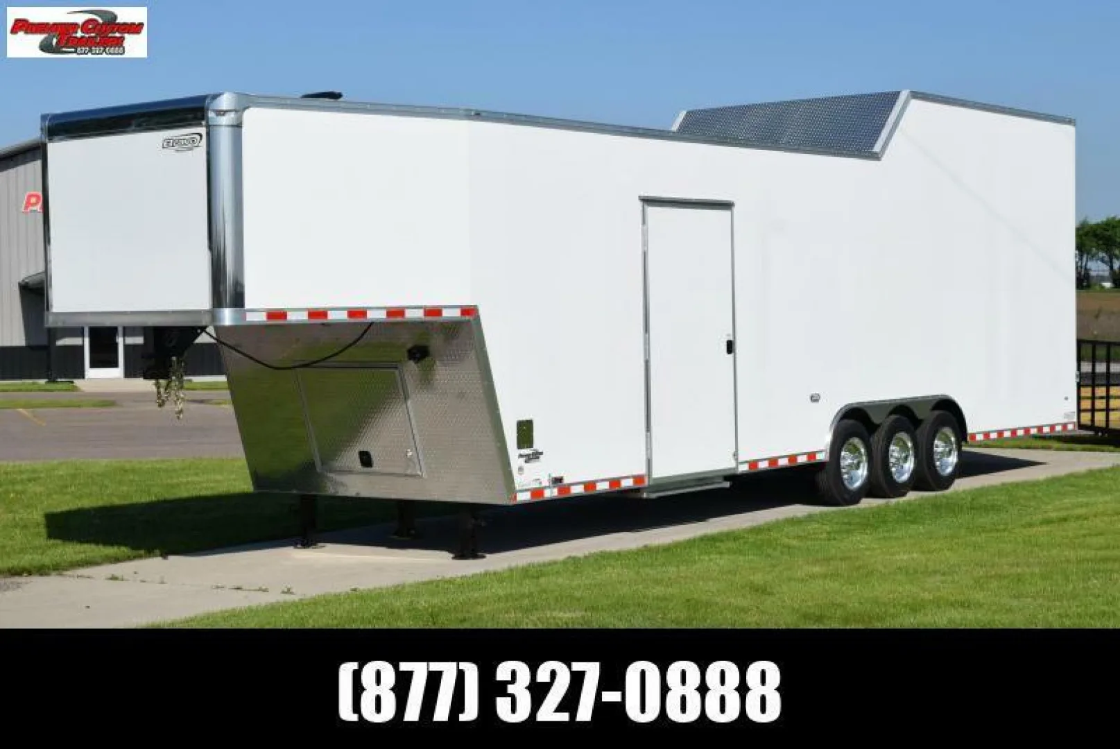 An all-white gooseneck trailer sits on the sales property ready for a buyer. It's sunny outside and the trailer is closed.
