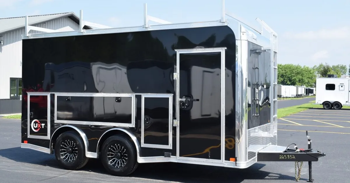A landscape view of a black contractor trailer parked on the sales lot. The trailer features various doors for storage. A landscape view of a black contractor trailer parked on the sales lot. The trailer features various doors for storage.