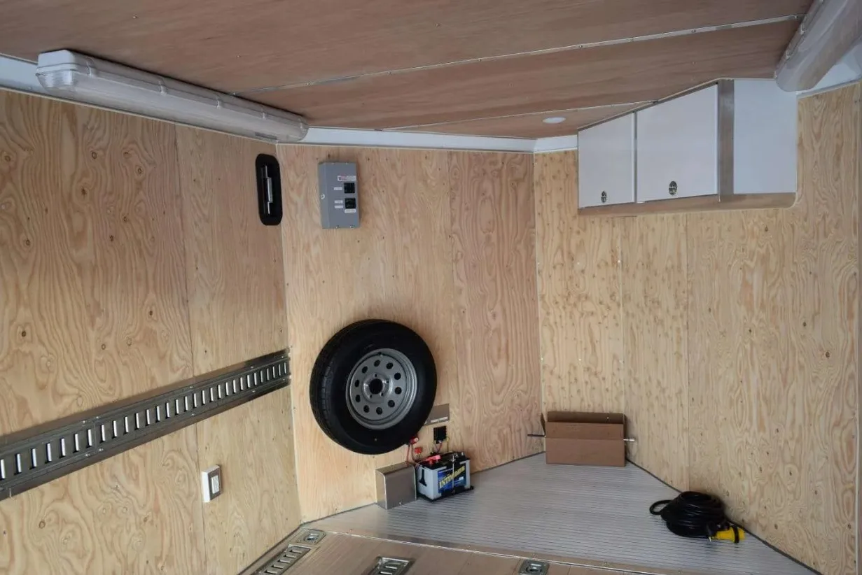 The inside of a customized trailer with the wood underlay surrounding the walls and cabinet placements.