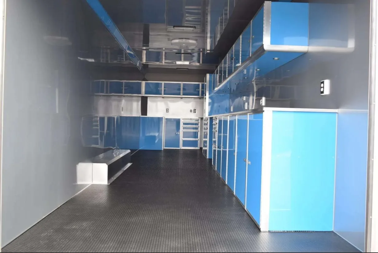The interior of a custom trailer open with custom cabinetry in a blue laminate material with silver trim.